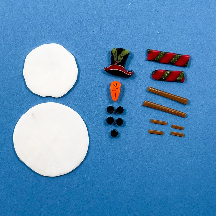 Separated snowman components with white body pieces, hat, scarf and carrot nose, Bullseye 90COE